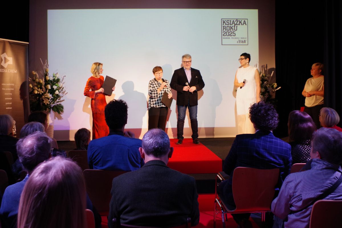 Na scenie cztery kobiety i mężczyzna, kwiaty, czerwony dywan, w tle ściana z napisem: Książka Roku 2025