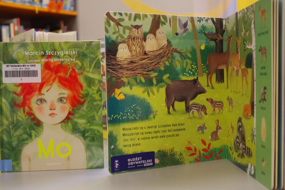 Dwie książki stojące na swoich brzegach, jedna otwarta z granatową naklejką Budżet Obywatelski