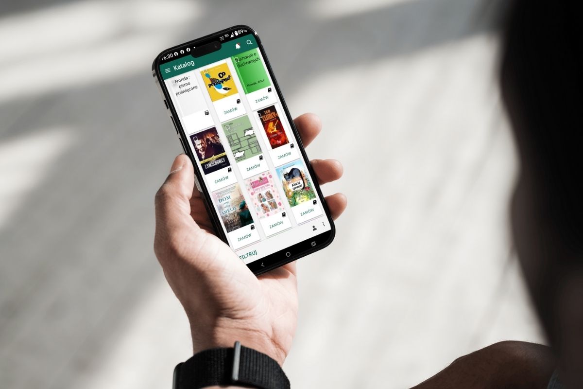 Ręka trzymająca telefon komórkowy z działającą aplikacją biblioteczną mProlib