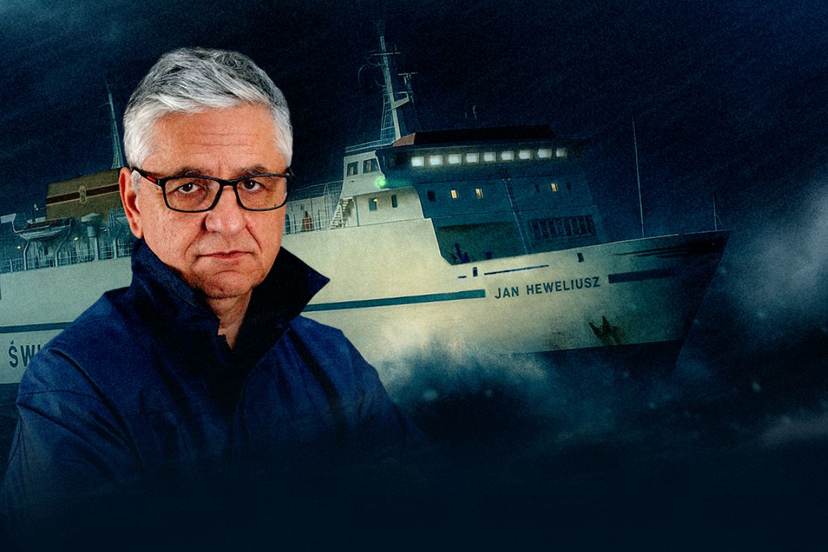 Na tle promu Heweliusz podczas sztormu mężczyzna w okularach w granatowej bluzie