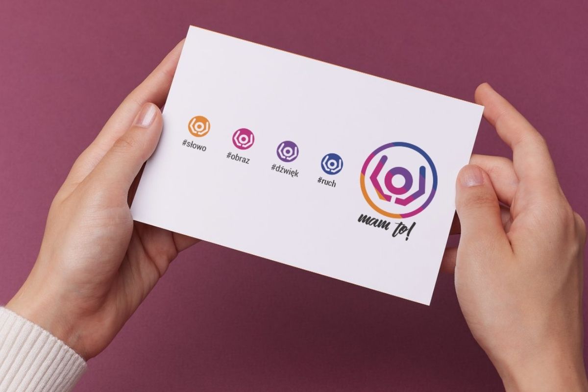 Na fioletowym tle ręce trzymające kartkę z symbolami festiwalu MAM to! 