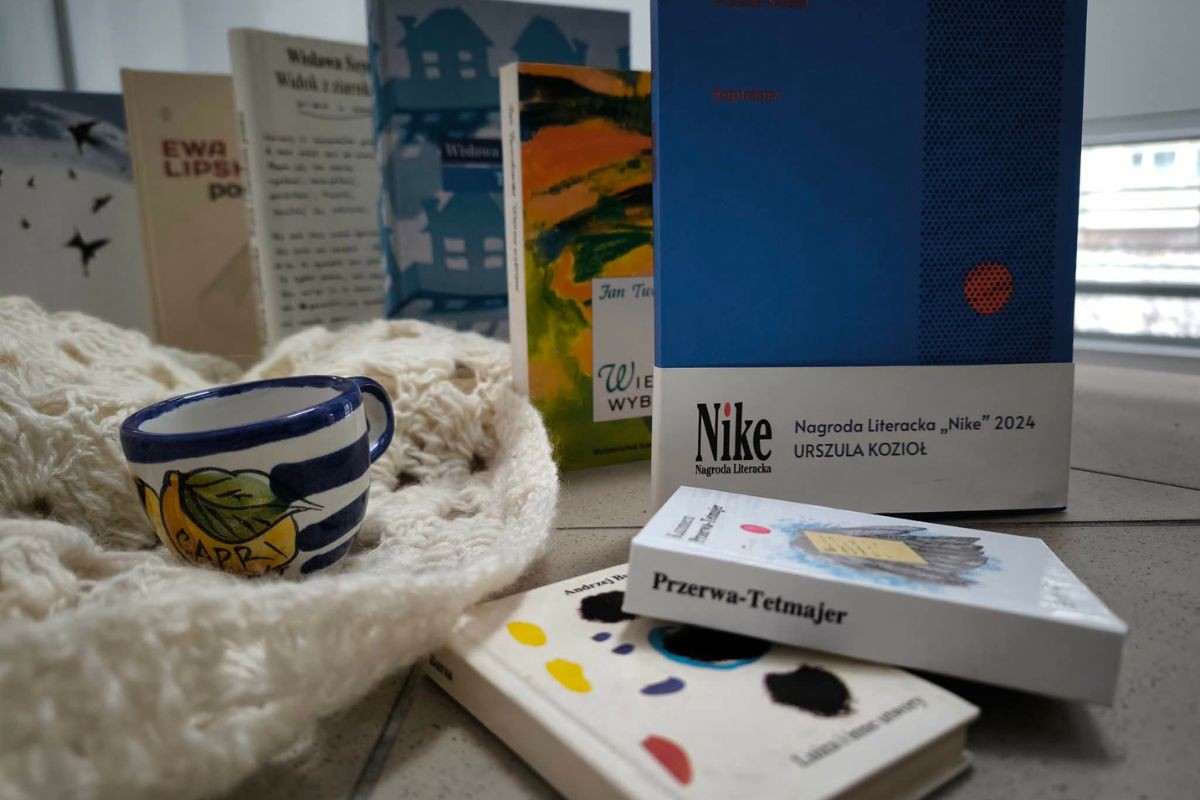 Leżące i stojące tomiki poezji, z lewej biały koc i filiżanka