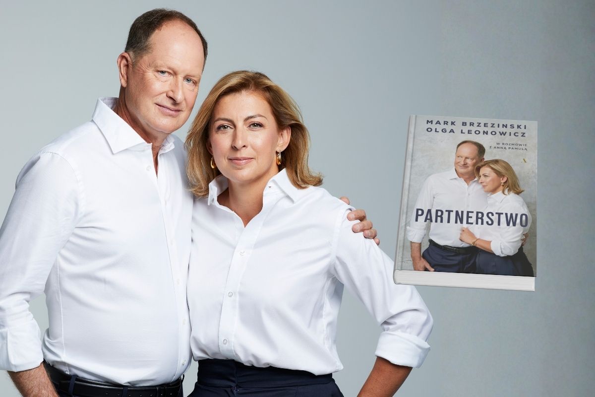 Na szarym tle przytuleni mężczyzna i kobieta w białych koszulach, z prawej okładka książki