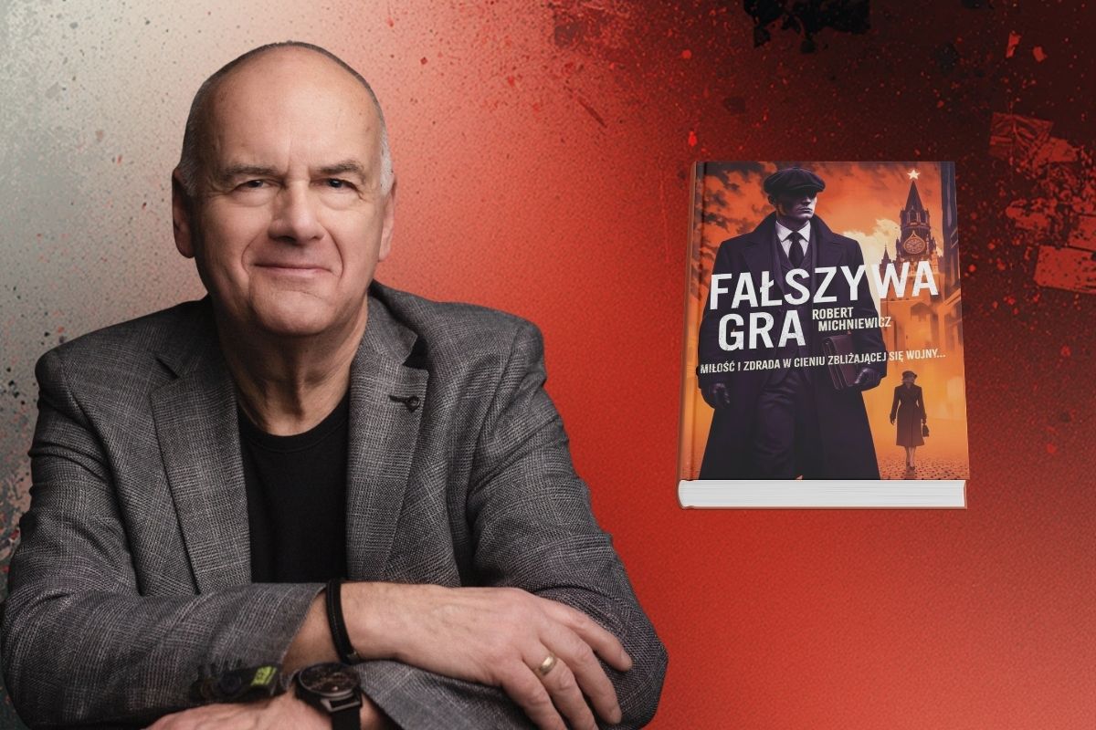 Uśmiechnięty mężczyzna w beżowej marynarce z założonymi z przodu rękami, z prawej okładka książki, tło beżowo-czerwone