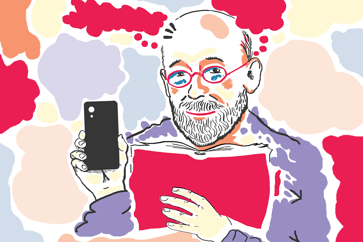 Mężczyzna w okularach i z brodą trzymający książkę i smartfon, w tle kolorowe plamy 