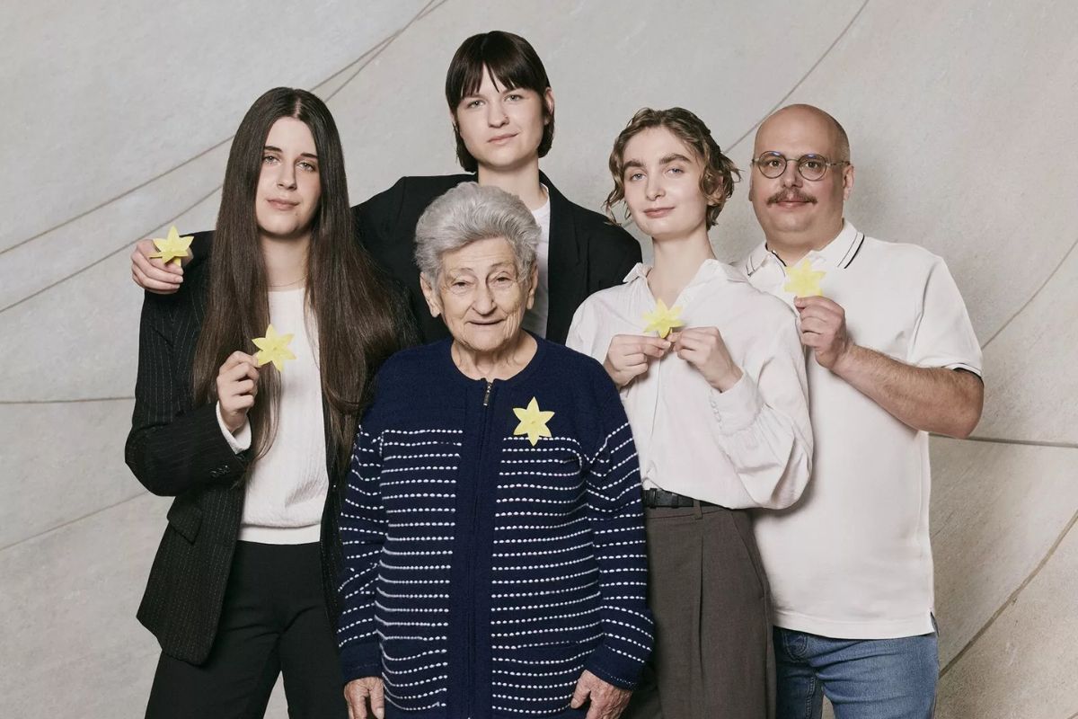 Trzy młode kobiety, jeden mężczyzna w okularach i starsza pani, każdy trzyma w ręku papierowego żonkila