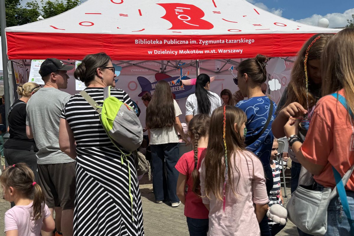 Namiot biblioteczny na pikniku, duża grupa osób stojących tyłem 