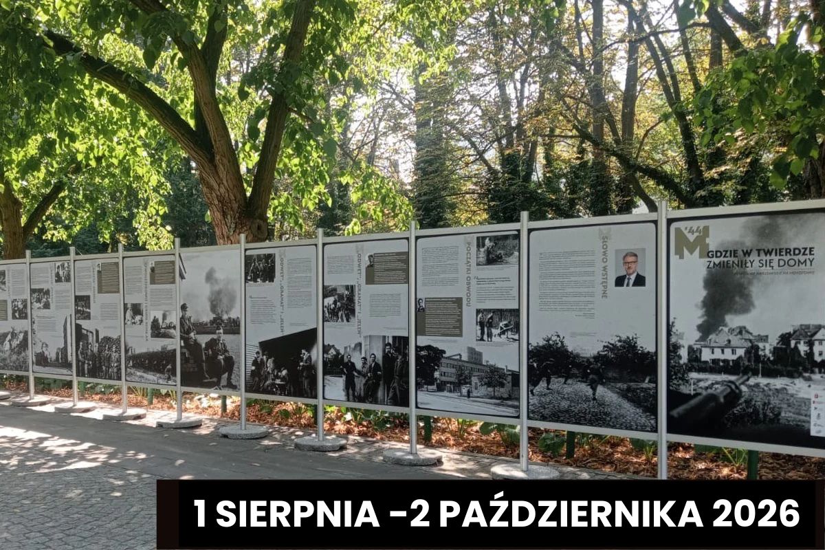 Plansze wystawy o Powstaniu Warszawskim stojące na tle drzew w parku Dreszera, napis: 1 sierpnia-2 października 2026