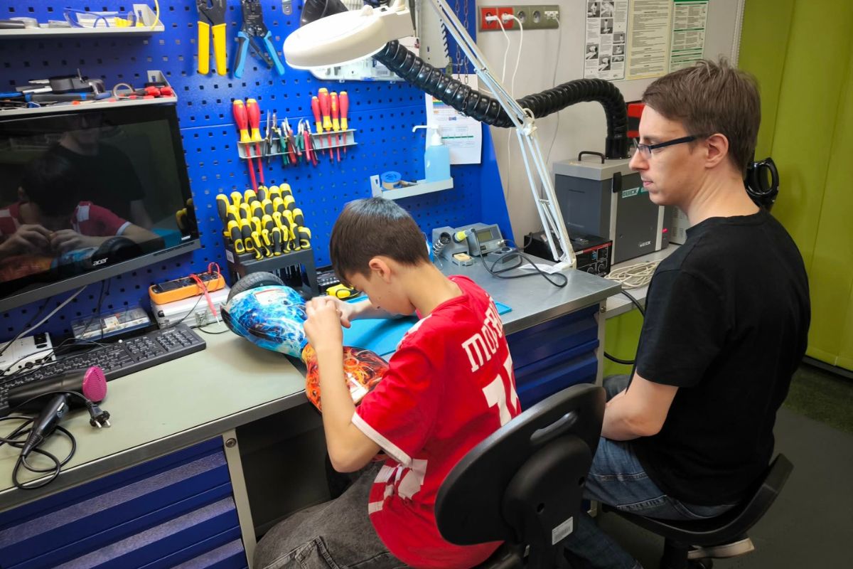 Dwie osoby naprawiają sprzęt elektroniczny w warsztacie naprawczym