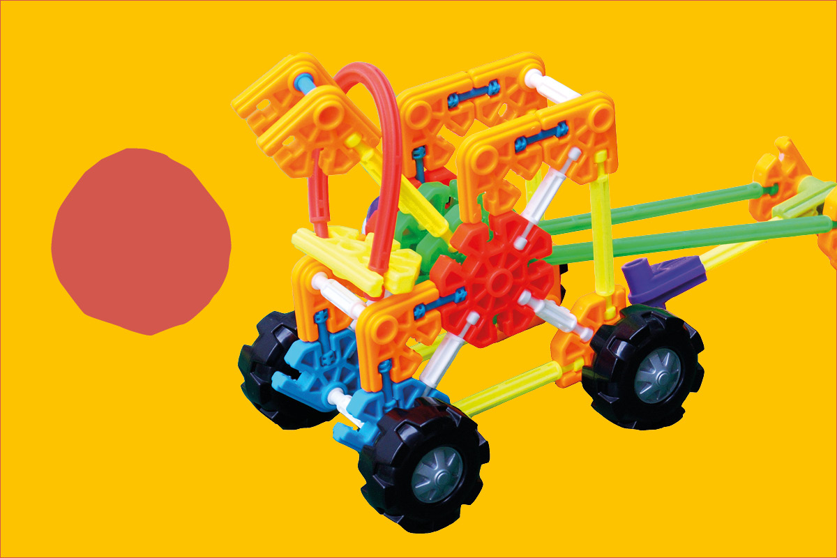 Pojazd skonstruowany z klocków Kid K'nex na żółtym tle; po lewej stronie czerwona plama
