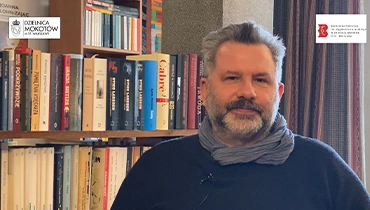 Na zdjęciu Michał Zając na tle książek
