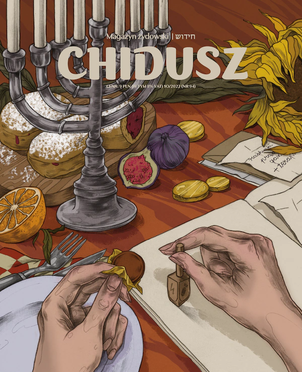 Okładka jednego z numerów magazynu Chidusz. Narysowany stół, na którym leżą różne owoce i wypieki. Na stole stoi też siedmioramienny świecznik. Lewa ręka trzyma w dłoni ciasteczko. Prawa dłoń kręci drewnianym bączkiem.