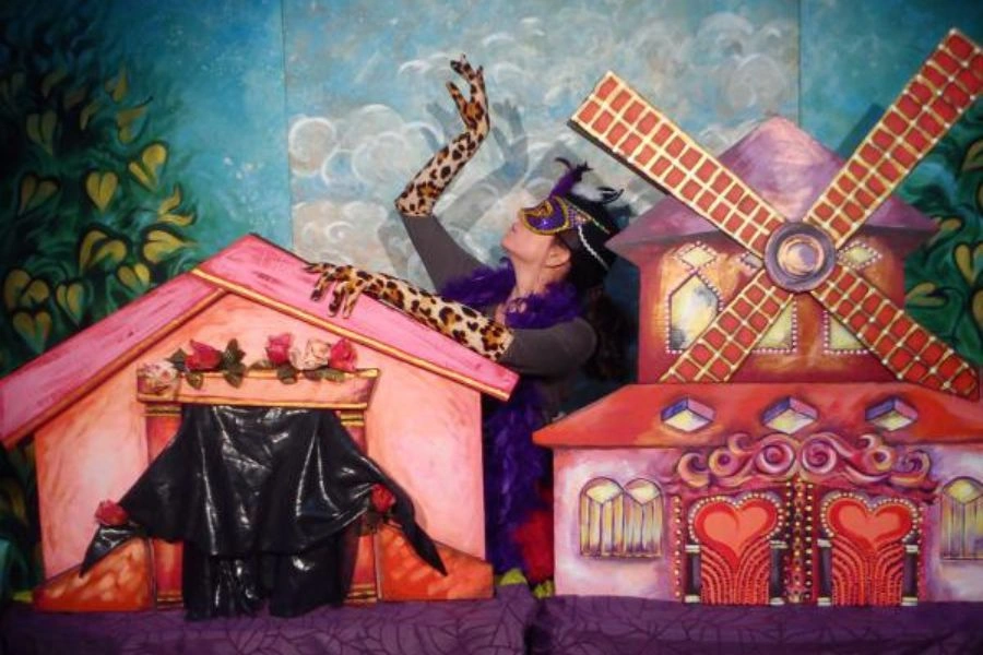 Aktorka w masce, wokół niej dekoracje teatralne
