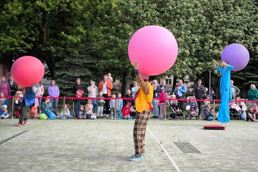 Przedstawienie cyrkowe, klauni z balonami na głowach, w tle publiczność