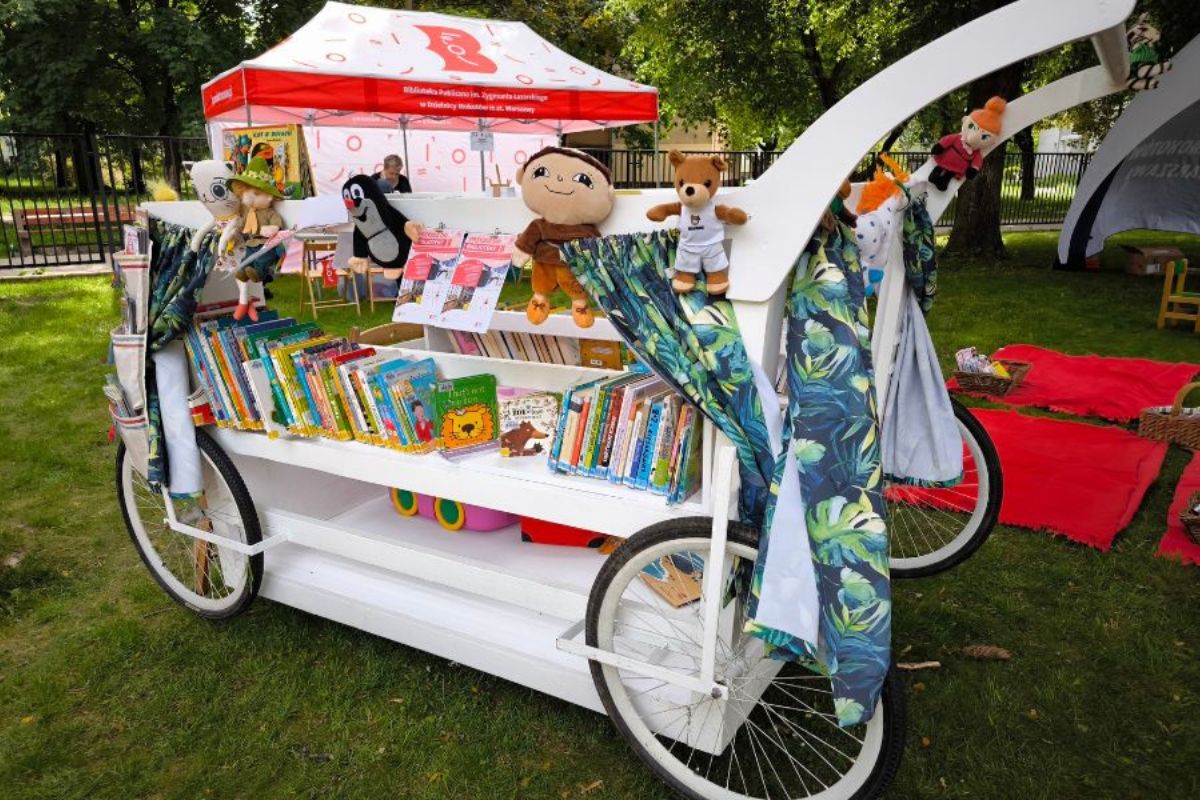 Mobilny wózek biblioteczny z książkami i maskotkami