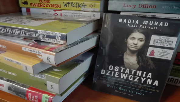 Kilka książek na stosie i okładka książki Ostatnia dziewczyna.