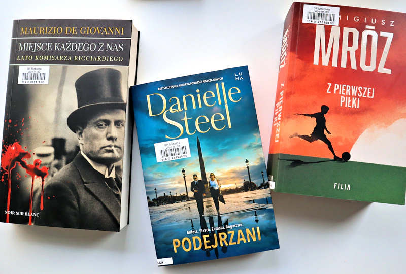 Na białym blacie leżą trzy kryminały: Remigiusza Mroza, Danielle Steel, Maurizio de Giovanni.