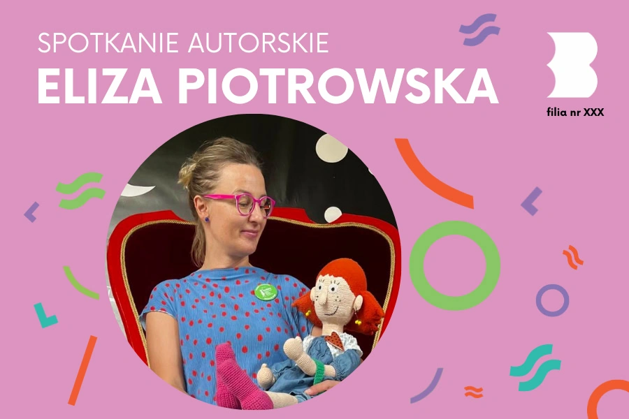 Na czarno-czerwonym fotelu siedzi kobieta w okularach, która wpatruje się w roześmianą rudowłosą lalkę szmacianą.