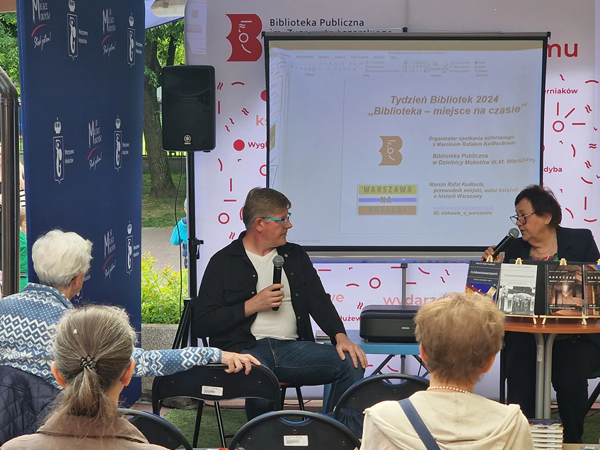Spotkanie autorskie, na którym prelegent z mikrofonem w ręku o czymś opowiada gościom.