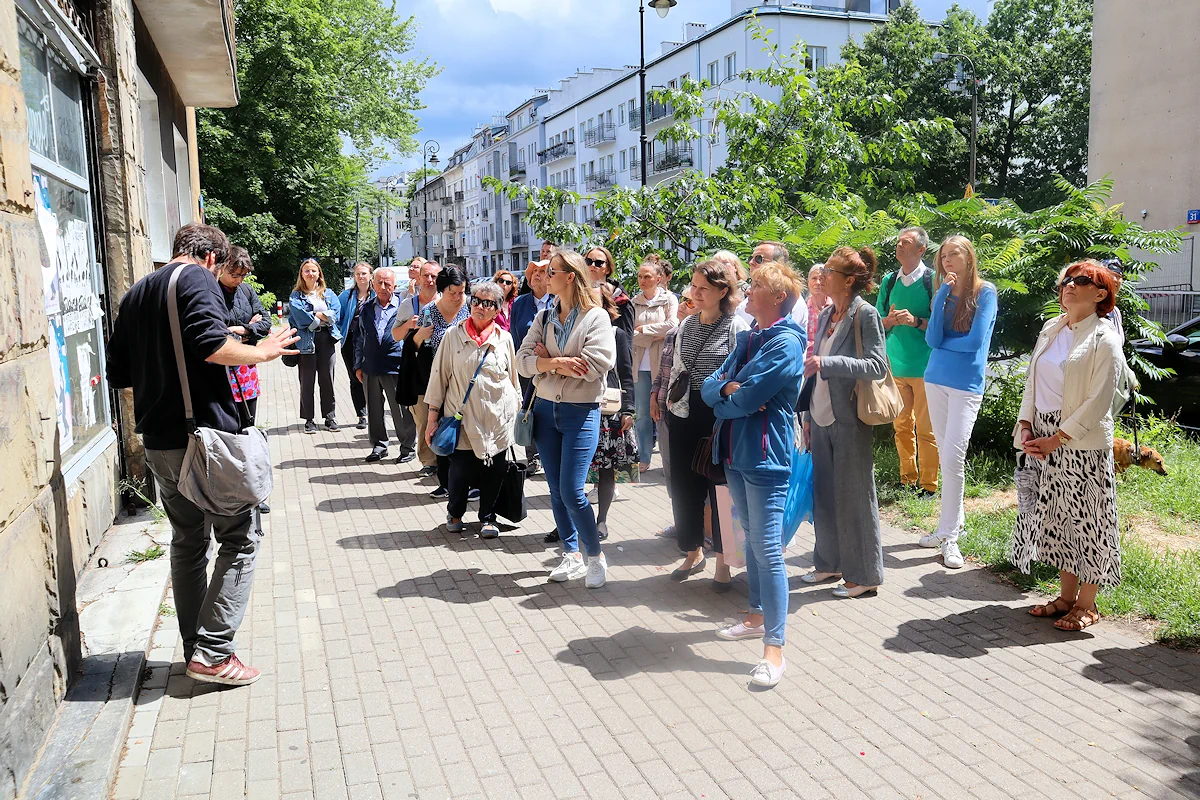 Grupa ludzi zgromadzona przed oryginalną fasadą historycznego budynku na Narbutta.