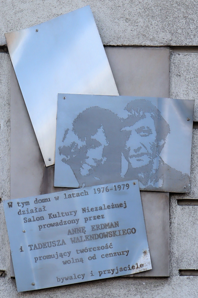 Do ściany budynku przymocowano trzy jakby losowo przymocowane blachy w sinoniebieskiej tonacji. Krzywo przymocowana górna, częściowo przykryta środkową, jest całkowicie pusta. Na środkowej, prawie równoległej do poziomu, widnieją portrety kobiety i mężczyzny. Na dolnej, krzywo położonej tablicy widnieje tekst: W tym domu w latach 1976 - 1979 działał Salon Kultury Niezależnej prowadzony przez Annę Erdman i Tadeusza Walendowskiego promujący twórczość wolną od cenzury; bywalcy i przyjaciele.