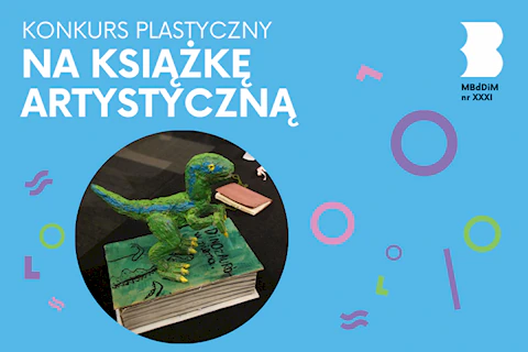 Na grubej książce w zielonej oprawie stoi figurka zielonego dinozaura.