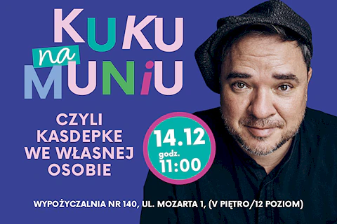 Ciemnowłosy mężczyzna z krótką brodą, w czarnej koszuli i czapką na głowie uśmiecha się wprost do obiektywu.