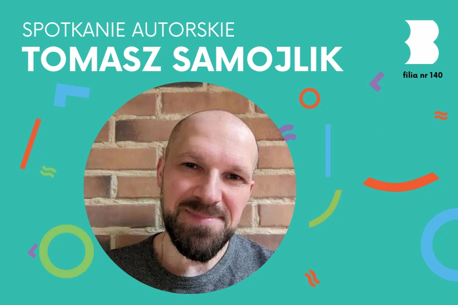 Łysawy mężczyzna z brodą i wąsami uśmiecha się serdecznie do obiektywu.