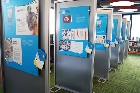 Zdjęcie ścianek wystawienniczych, prezentujących nagrodzone książki. W tle widać salę biblioteczną.
