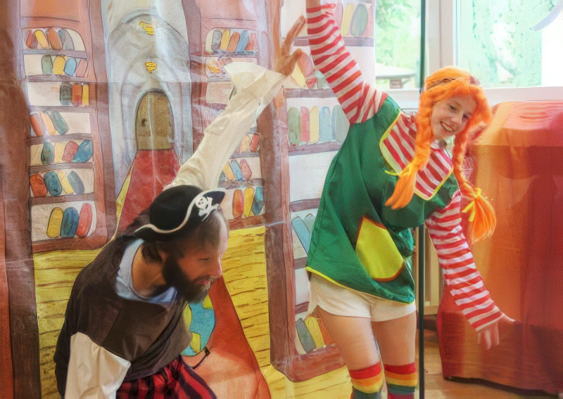 Aktor grający pirata tańcuje razem z pomarańczowowłosą Pippi w pstrokatym stroju.