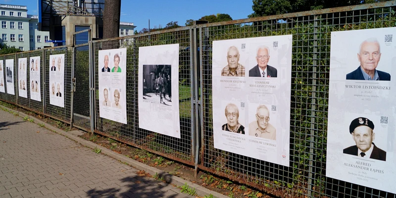 Druciany płot, a na nim kilka plansz ze zdjęciami powstańców z Mokotowa.