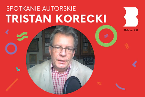 Dojrzały, siwiejący mężczyzna w okularach i białej marynarce, mówi coś do mikrofonu.