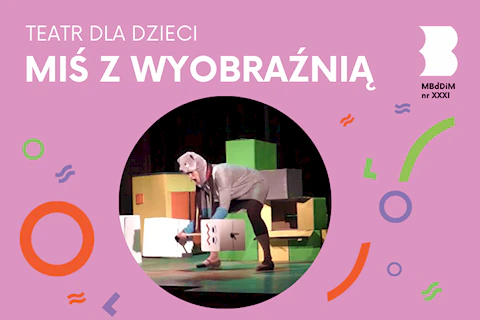 Aktorka przebrana za szarego misia podnosi sztangę z kartowymi ciężarkami, za sobą mając kolorowe pudła.