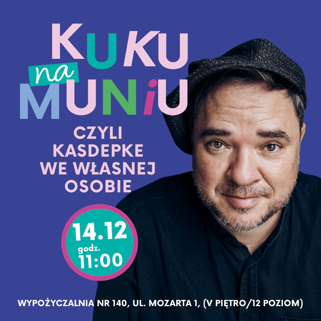 Ciemnowłosy mężczyzna z krótką brodą, w czarnej koszuli i czapką na głowie uśmiecha się wprost do obiektywu.